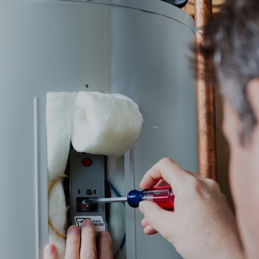 Man-adjusting-temperature-on-water-heater-with-screwdriver